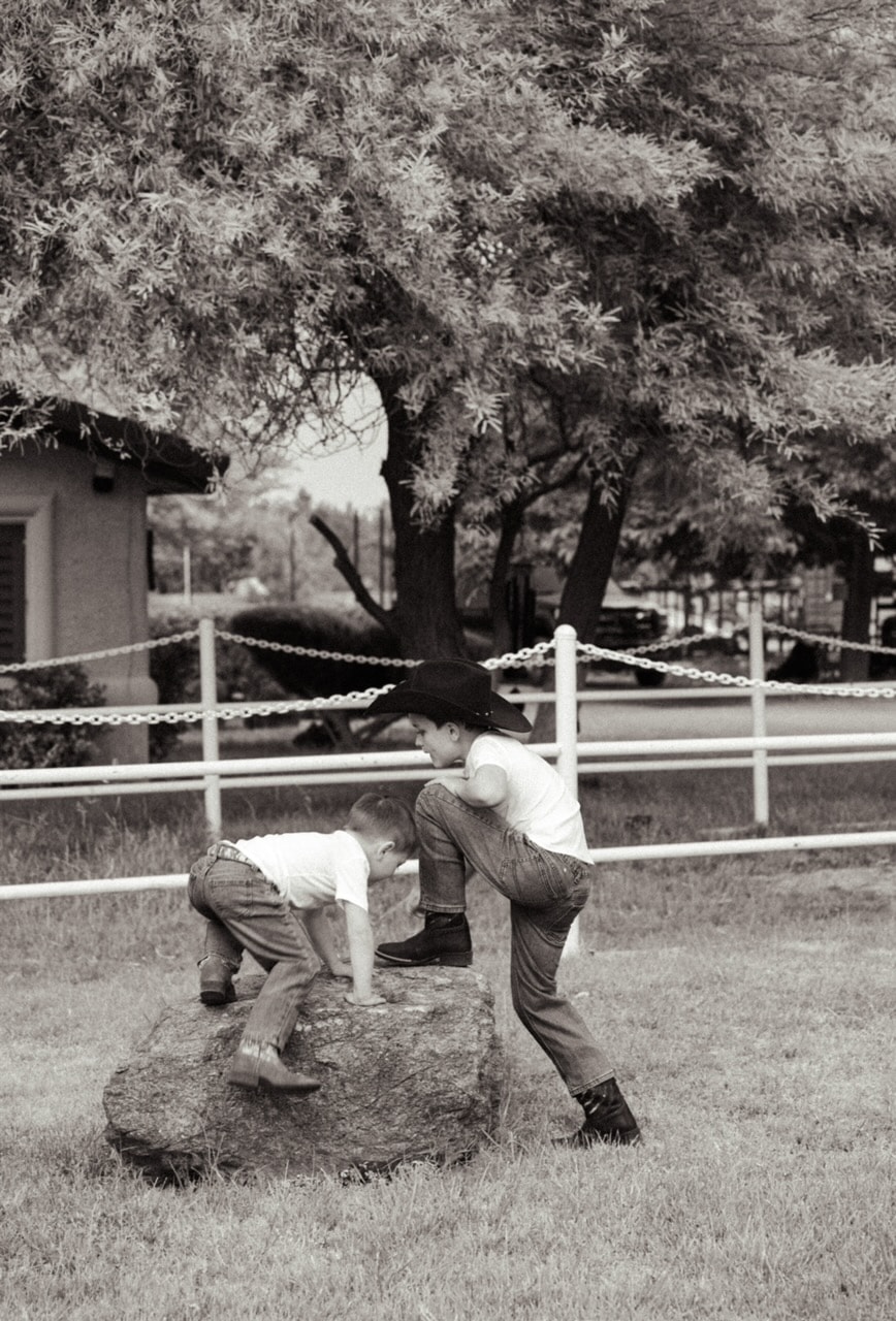 Two young cowboys playing on a rock at Windrock Farm birthday party