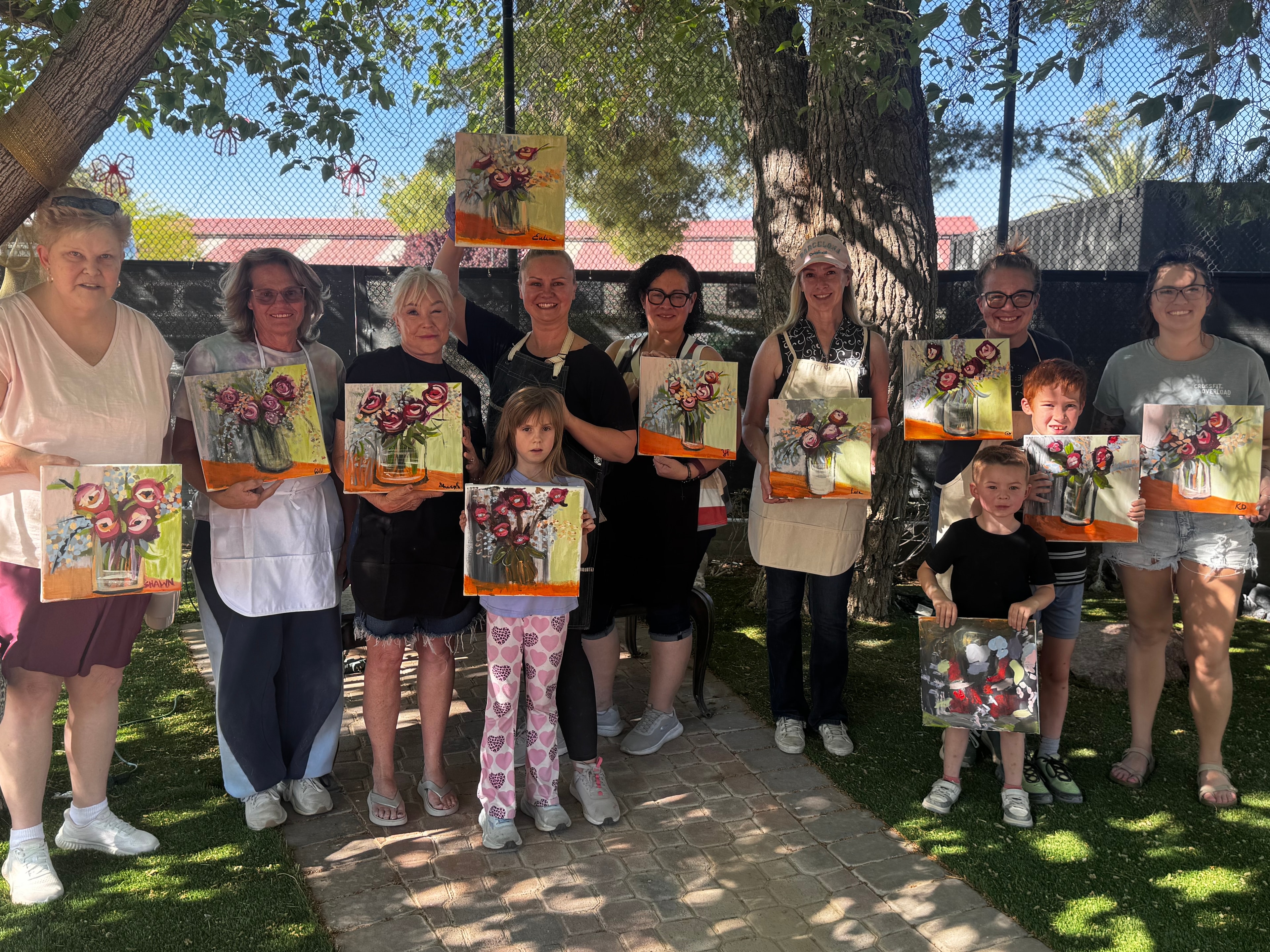 Group of participants proudly showing their flower paintings at a Paint With Me party at Windrock Farm